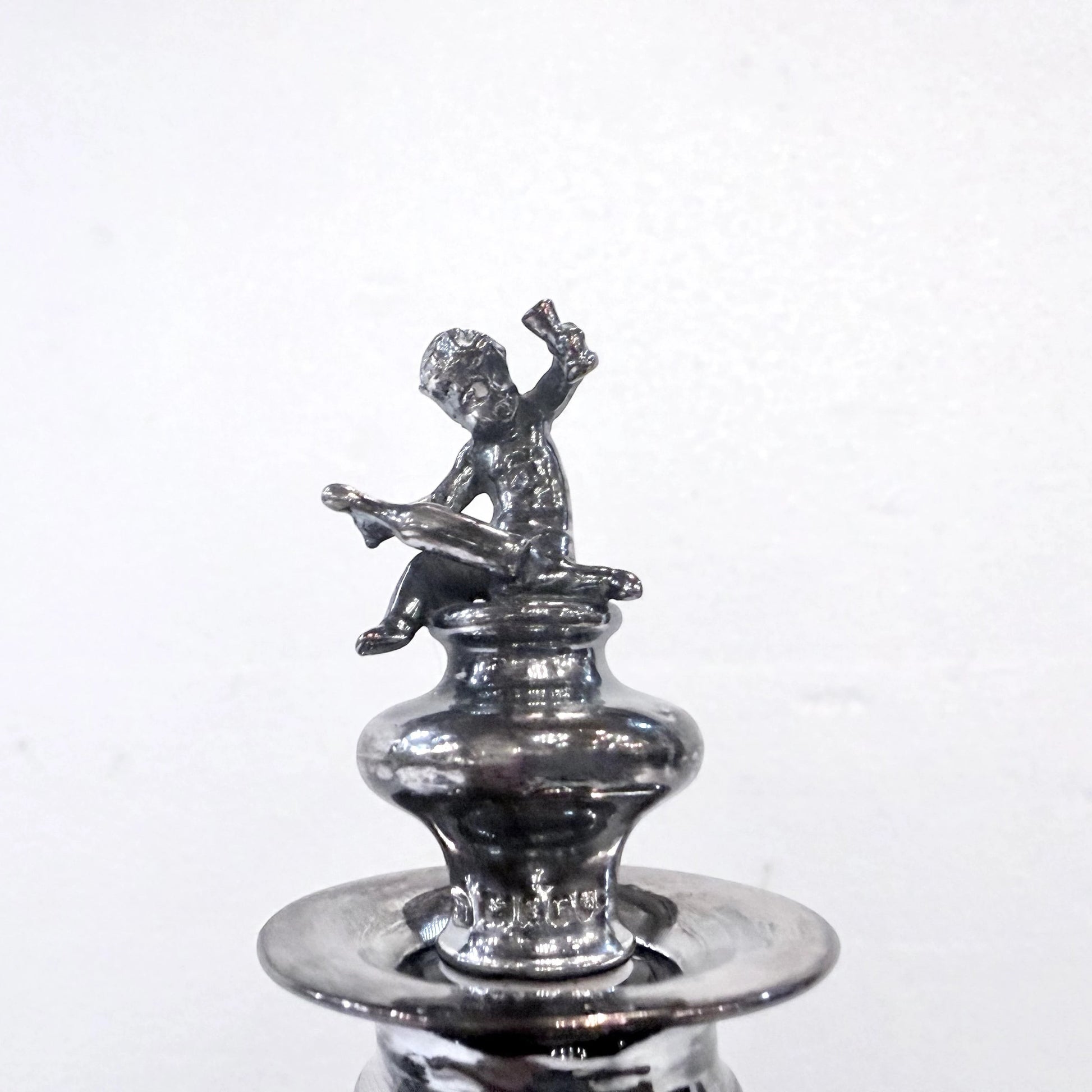 KLS Vaults antique 1902 sterling silver stopper featuring a seated putto finial on an Edwardian glass decanter