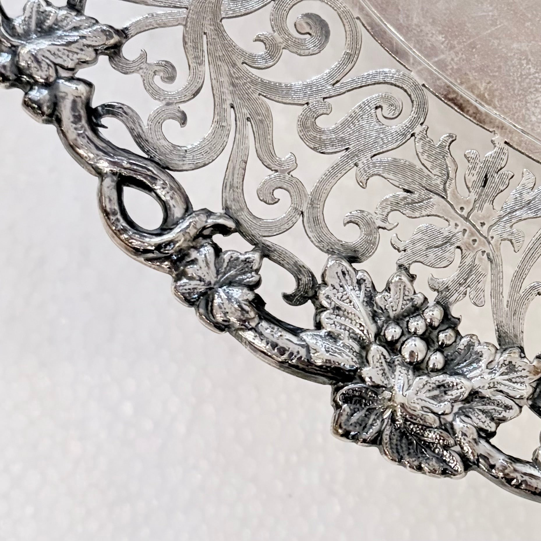 KLS Vaults sterling silver tazza detail featuring intricate pierced scrolling vines and grape cluster border.