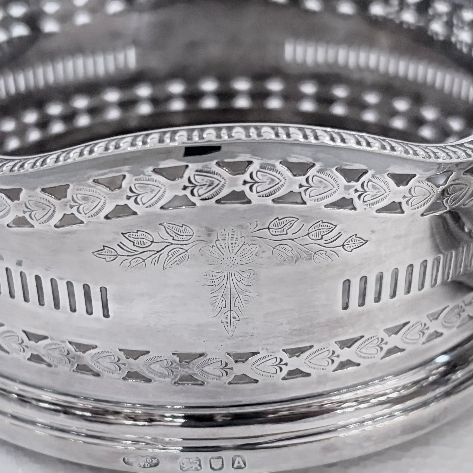 KLS Vaults pair of 1936 sterling silver wine coasters with intricate pierced fretwork and engraved foliate motifs.