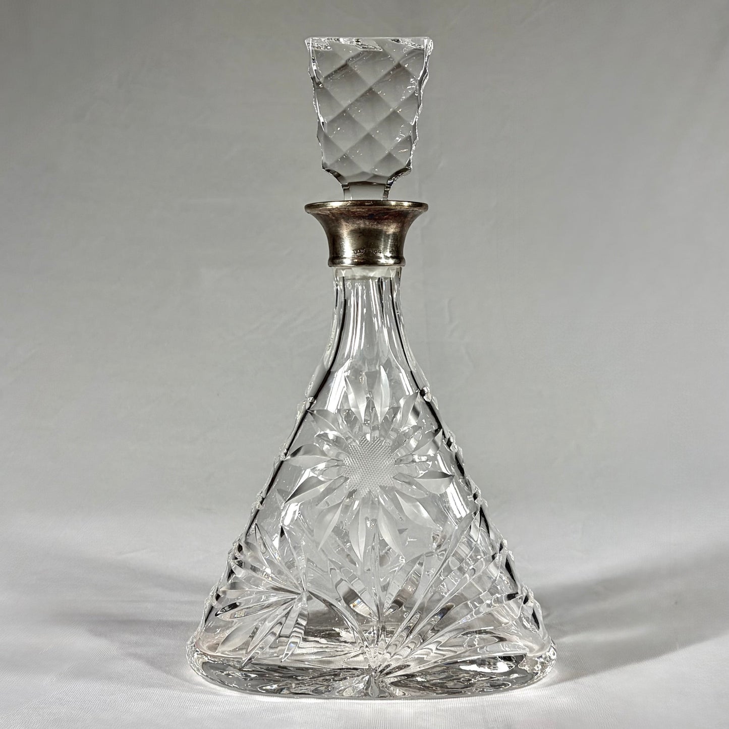 KLS Vaults triangular cut-glass decanter with sterling silver collar, floral rosettes, and geometric stopper, 1968.
