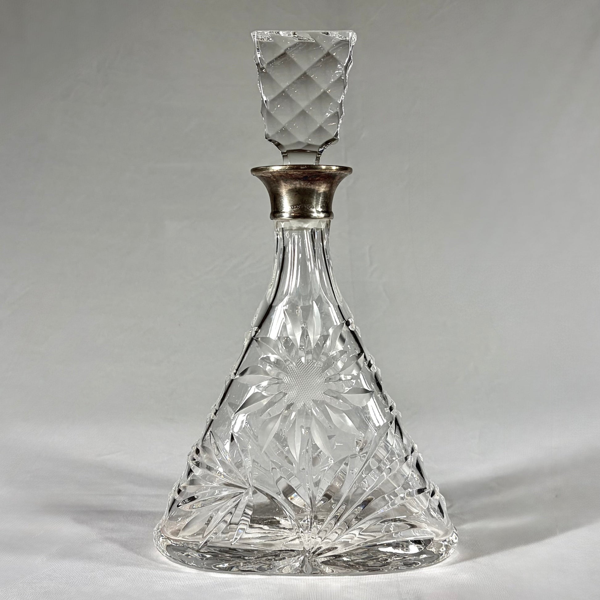 KLS Vaults triangular cut-glass decanter with sterling silver collar, floral rosettes, and geometric stopper, 1968.