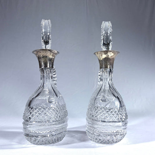 KLS Vaults pair of Victorian diamond-cut crystal claret jugs with silver-mounted collars and oversized glass stoppers.