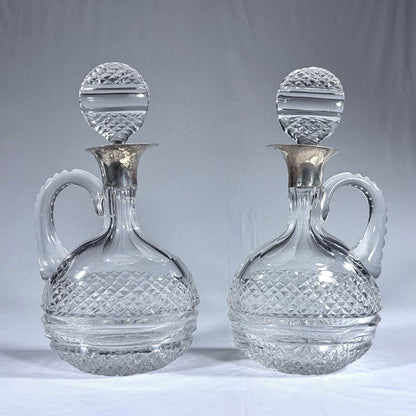 KLS Vaults pair of Victorian diamond-cut crystal claret jugs with silver collars and matching disc-form stoppers.