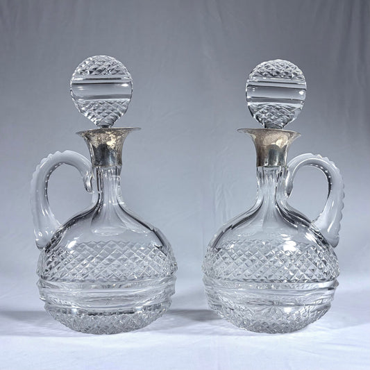 KLS Vaults pair of Victorian diamond-cut crystal claret jugs with silver collars and matching disc-form stoppers.