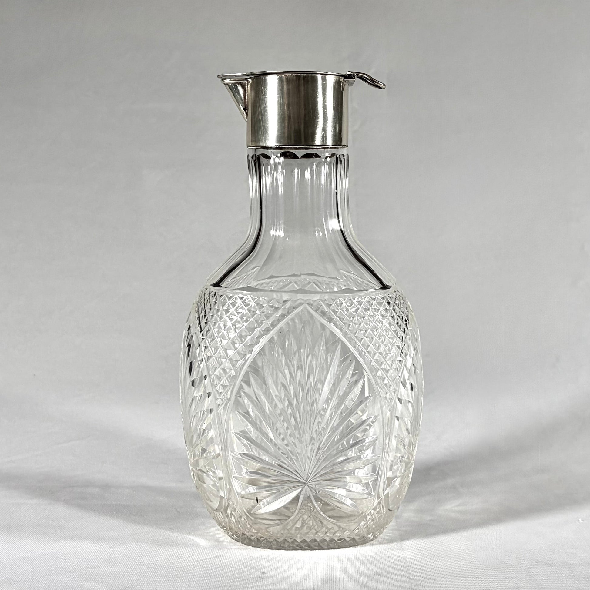 KLS Vaults Victorian claret jug with diamond-cut crystal body and sterling silver hinged lid and pouring spout.